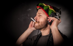 Мужчина растаман в наушниках с сигаретой 