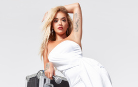 Певица Рита Ора в белом платье с микрофоном