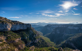 Яркое солнце в голубом небе над высокими горами 