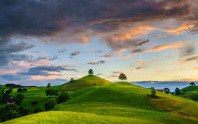 Зеленые холмы с деревьями под небом с грозовыми облаками
