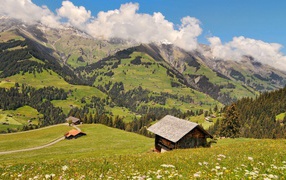Дом на зеленом холме в горах под белыми облаками