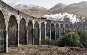 Паровоз едет по старому акведуку в горах 