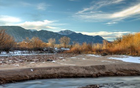 Каменный берег реки на фоне гор под голубым небом 