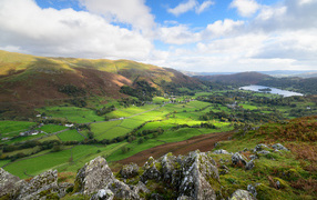 Вид на зеленые холмы под голубым небом с белыми облаками летом