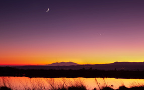 Молодой месяц в небе над озером ночью 