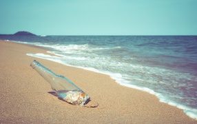 Бутылка с ракушками на песке у моря