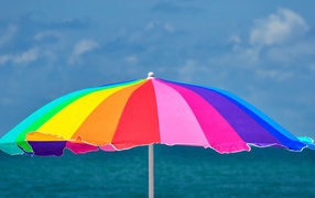 Large multi-colored beach umbrella on a background of the sea