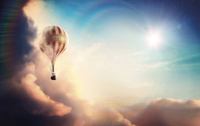 A large balloon flies above the clouds against the backdrop of the sun