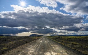 Long road under a blue sunny sky with white clouds in summer