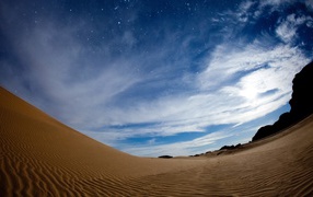 Wavy sand dune under a beautiful sky at dusk