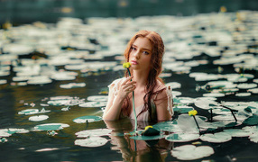 Красивая молодая девушка с водяными лилиями в пруду