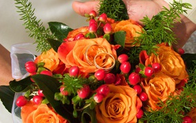 Букет оранжевых роз с красными ягодами и обручальными кольцами