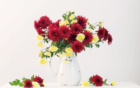 Букет красных и желтых хризантем в вазе на белом фоне