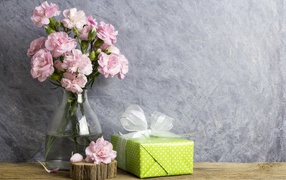 Розовые гвоздики с подарком на сером фоне