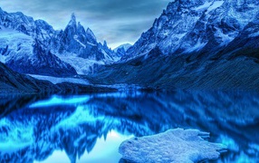 Голубой холодный закат на заснеженными горами у озера 