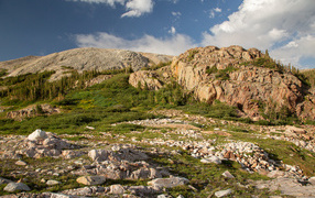Высокие каменные горы под  голубым небом с белыми облаками