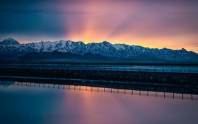 Заснеженные горы на рассвете у воды 