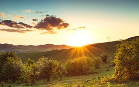 Яркое летнее солнце встает из-за гор 