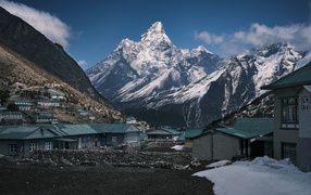 Поселок на фоне заснеженных гор под голубым небом 