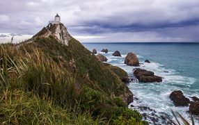 Маяк на вершине утеса у моря под грозовым небом