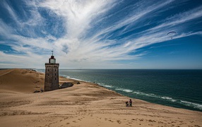 Lighthouse on the sand by the sea under the blue sky