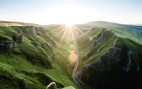 Дорога между покрытыми зеленью горами в лучах солнца