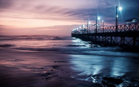 Вид на мост в океане с включенными фонарями ночью