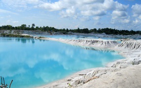 Белый песок на берегу водоема с голубой водой 