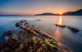 Спокойная вода в море с подводными камнями на закате 