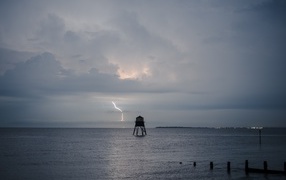 Old tower in the sea against the background of a thunderstorm