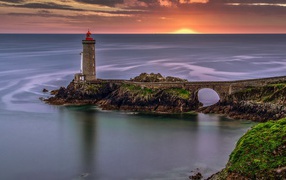 View of the calm sea and lighthouse at sunset
