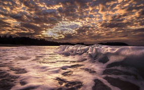 Белые волны на песке на рассвете 