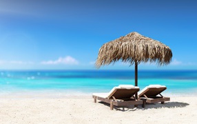 Два шезлонга под зонтом на пляже летом 