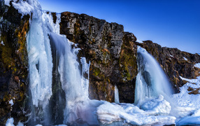 A frozen waterfall flows down from the mountains, Iceland