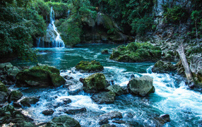 Голубая вода в водопаде стекает по камням 