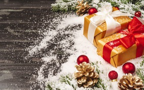 Два новогодних подарка на столе с еловыми ветками 