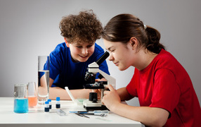 Мальчик и девочка смотрят в микроскоп 