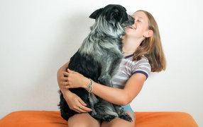 Веселая девочка с собакой в руках 