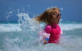 Веселая маленькая девочка купается в море летом