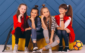 Четыре модных девочки сидят на диване 