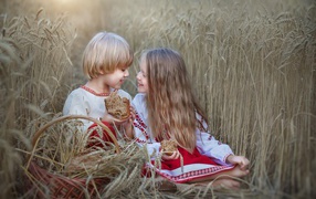 Маленькие мальчик и девочка с хлебом на пшеничном поле 