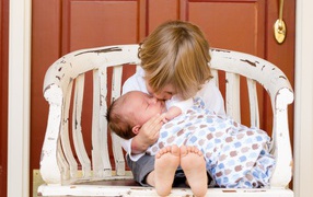 Маленькие мальчик держит брата на руках 