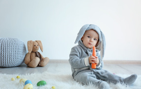 Маленький мальчик в костюме зайчика грызет морковь