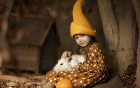 Маленькая смешная девочка в колпаке с кроликом