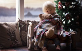 Маленькая девочка обнимает мишку у ели