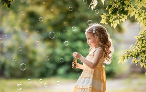 Маленькая девочка с мыльными пузырями в саду 