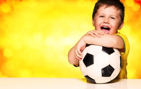 Маленький довольный мальчик с футбольным мячом