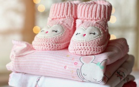 Маленькие розовые пинетки и одежда для малыша 