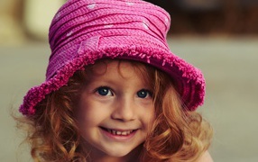 Маленькая улыбающаяся девочка в розовой шляпе