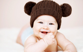 Улыбающийся грудной ребенок в коричневой шапке